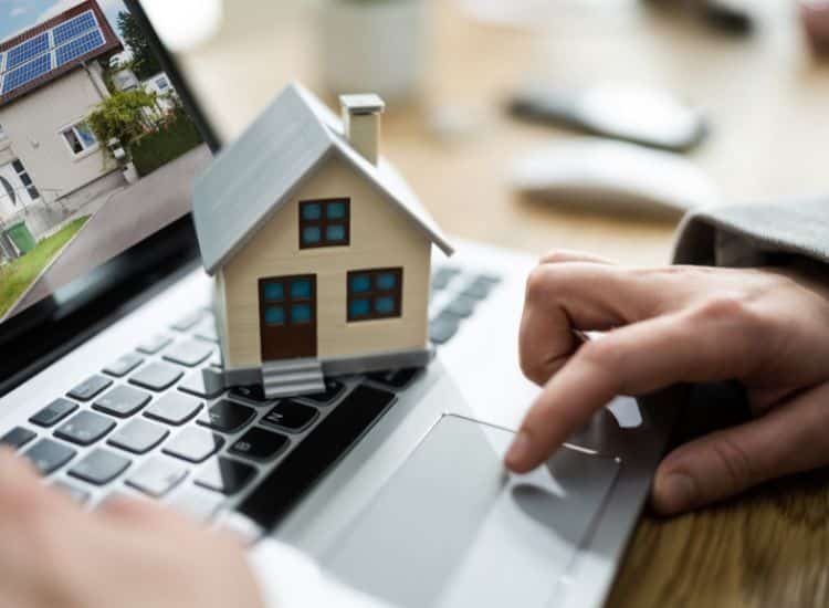 Mano sosteniendo un modelo de casa sobre un teclado, representando la integración de tecnología y servicios inmobiliarios en Coyoacán.
